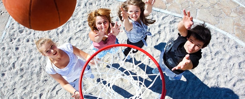 Top view of kids playing basketball. Check out the tips from Swingset Warehouse before buying a basketball system.