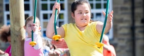 Overweight girl playing on a swing